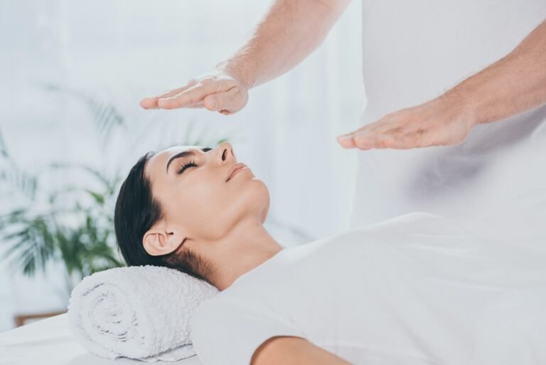 cropped shot of male healer doing reiki healing session to young woman with closed eyes